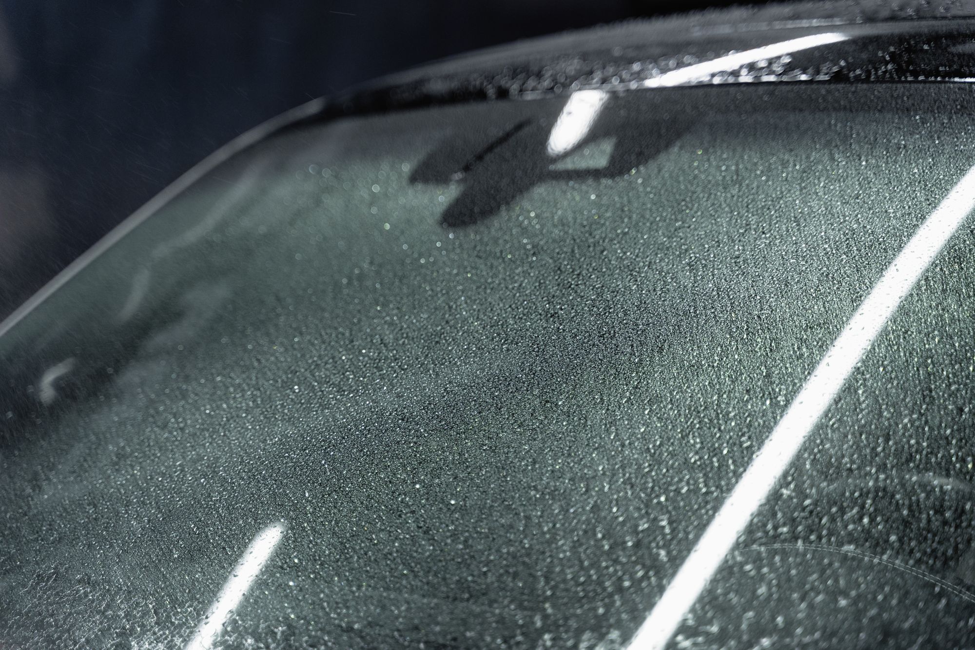 Donker autoglas met waterstrepen in strijklicht