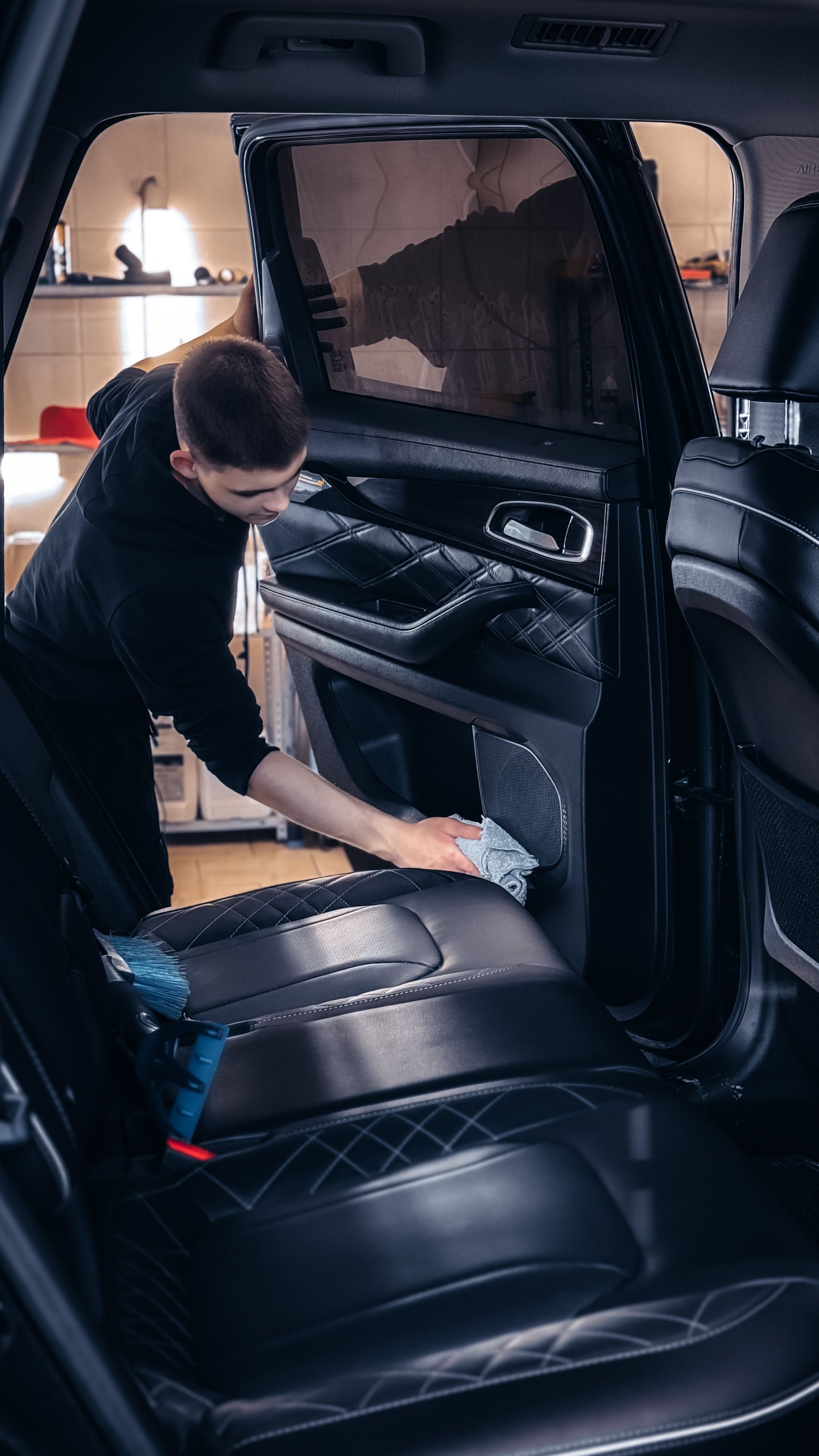 Medewerker reinigt het deurpaneel van een auto met een microvezeldoek