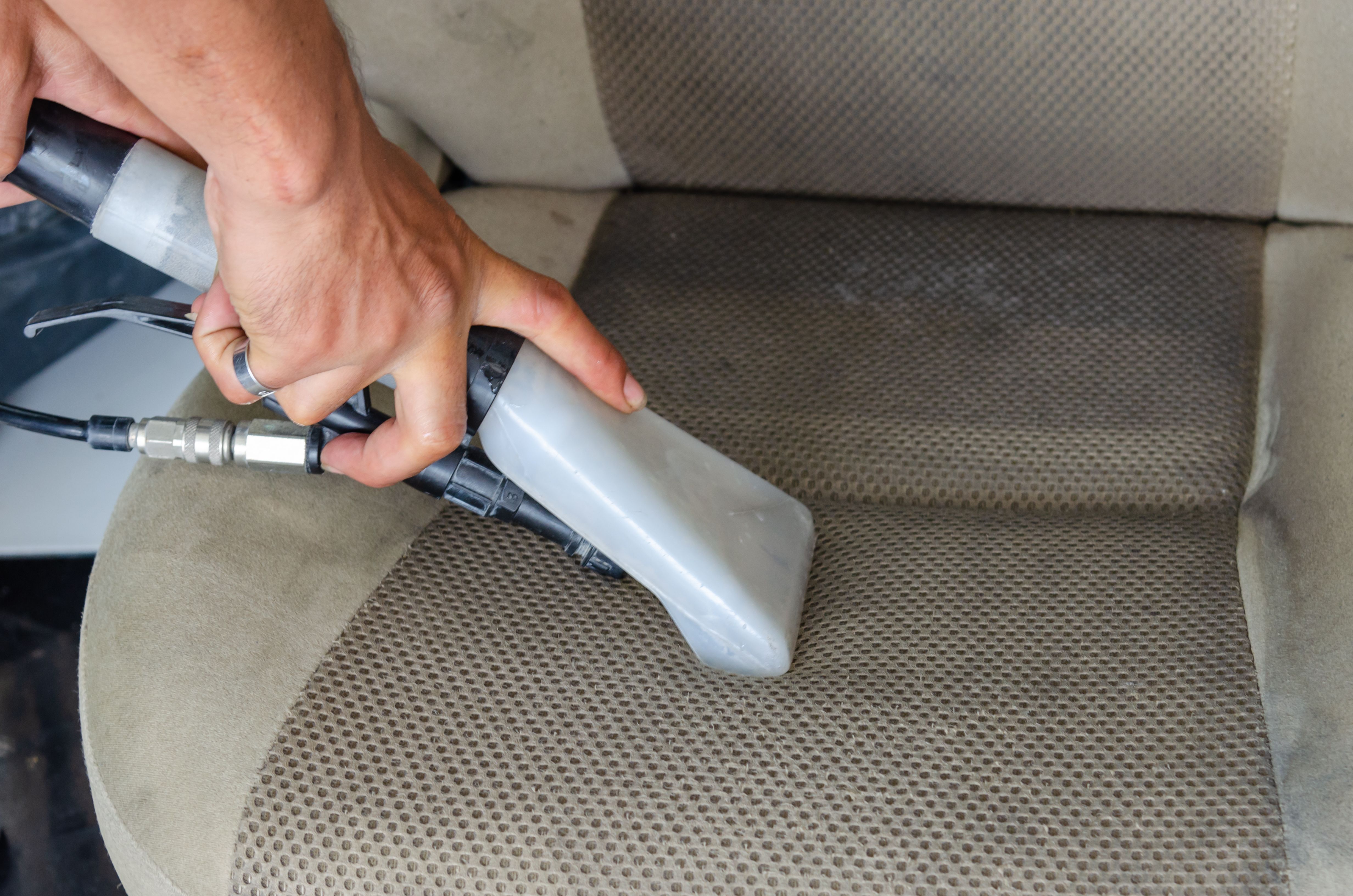 Bekleding van een autostoel wordt met een extractiezuiger gereinigd
